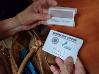 Zdjęcie kolorowe. Zbliżenie dłoni seniora, które trzymają etui na karty kredytowe.