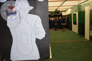Zdjęcie kolorowe. Z lewej strony tarcza strzelecka z białą postacią w tle uczniowie