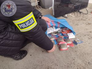 Zdjęcie kolorowe. Policjant liczy odzyskane włączniki i gniazdka elektryczne