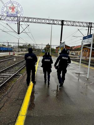 Zdjęcie kolorowe. Policjanci i funkcjonariusze SOK patrolujący peron
