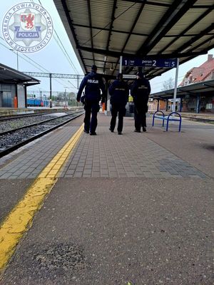 Zdjęcie kolorowe. Policjanci i funkcjonariusze SOK patrolujący peron