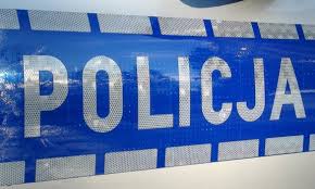 Zdjęcie kolorowe. Fragment policyjnego radiowozu - napis policja na niebieskim tle
